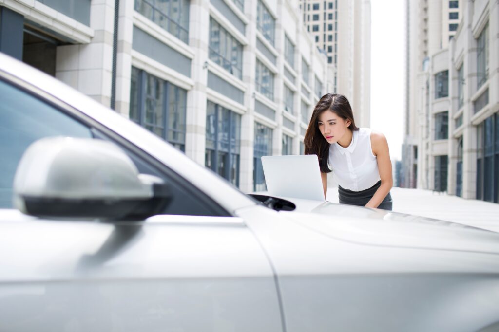 Confident businesswoman using laptop on car