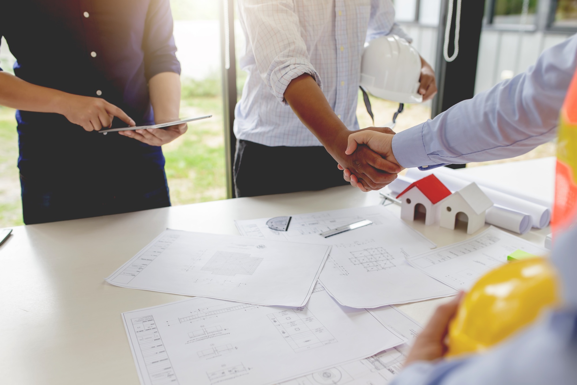 Investor and engineer shaking hands at meeting.