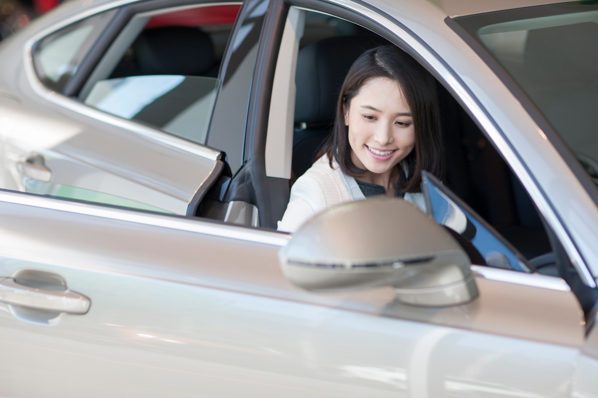 Young woman choosing car in showroom